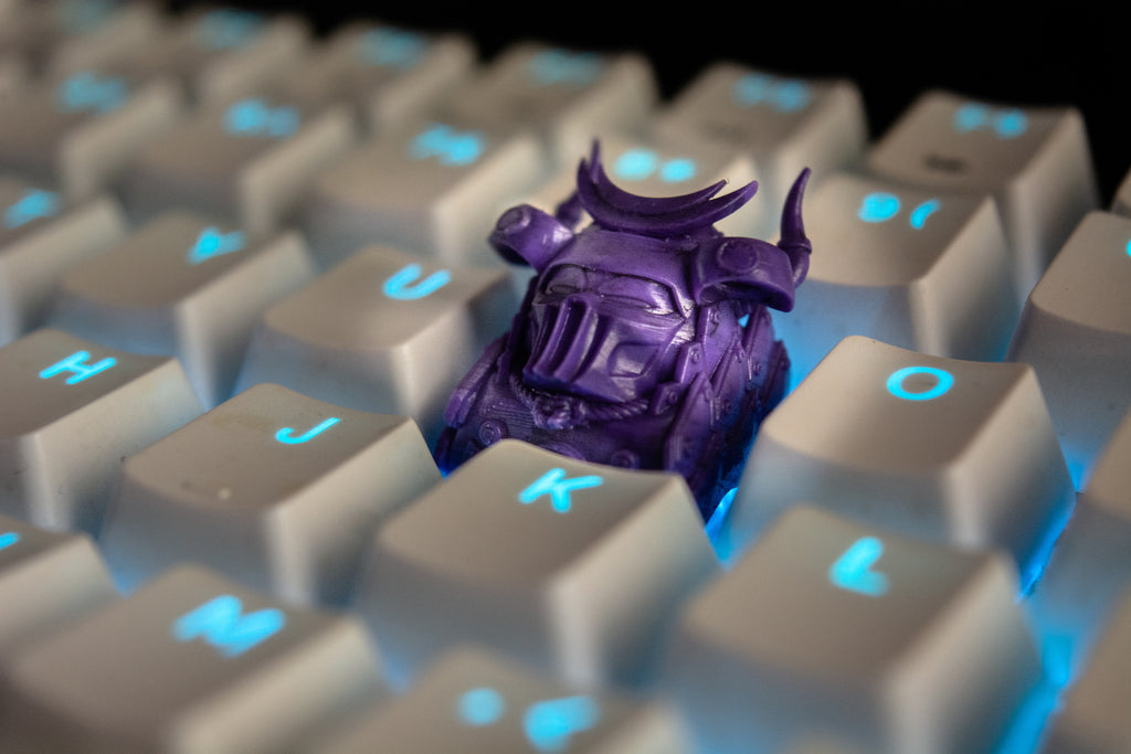 Purple samurai artisan keycap on a keyboard with blue backlighting