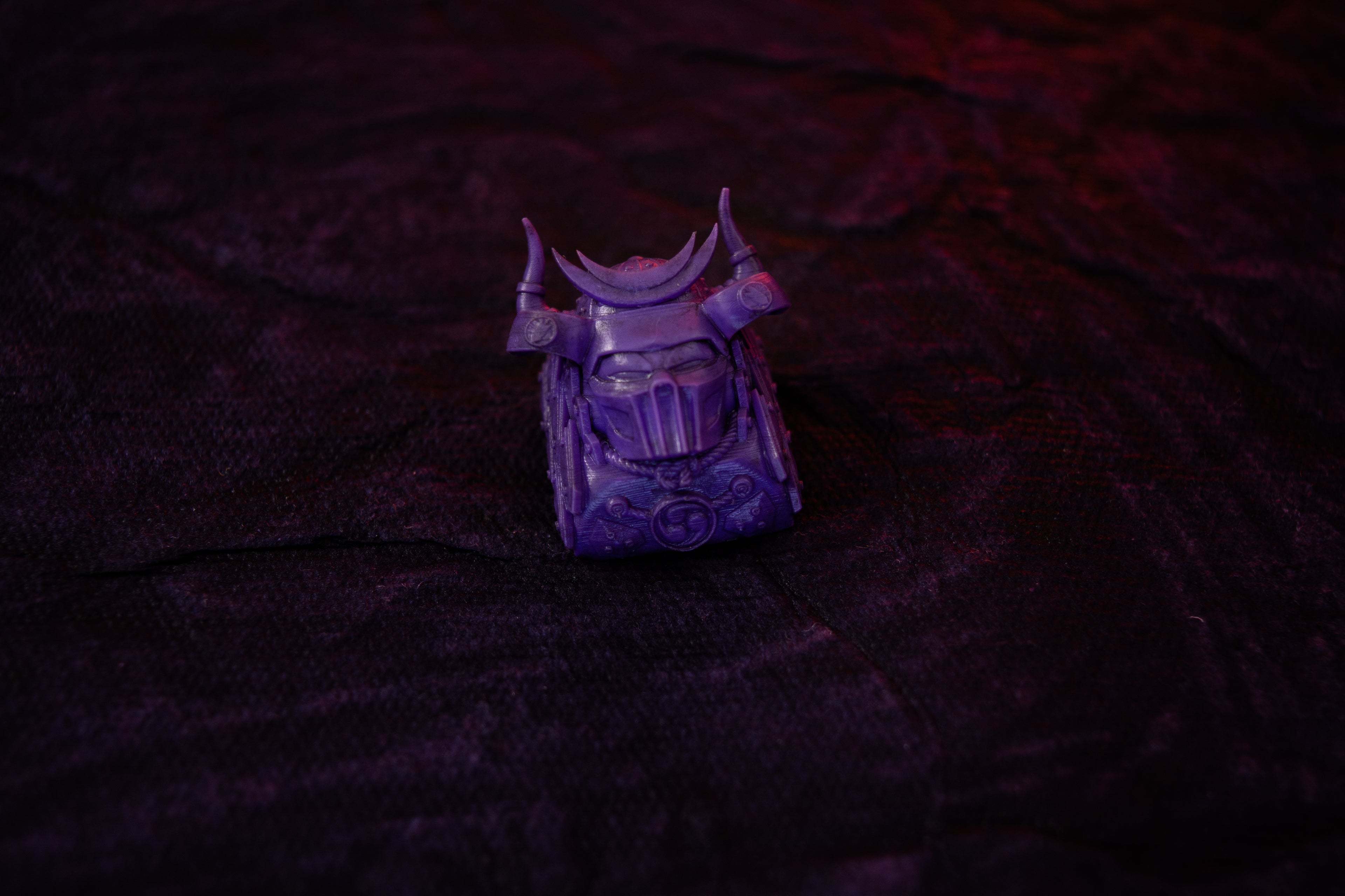 Purple keyabord decorative item (artisan keycap) on a textured dark surface